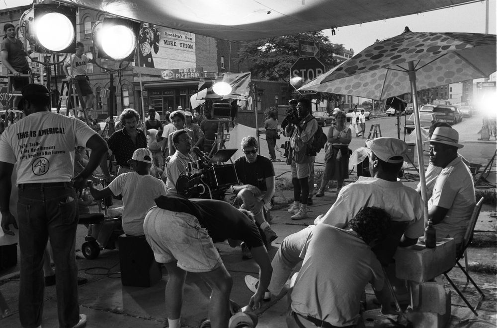 A film crew with lights and equipment on a street outside.