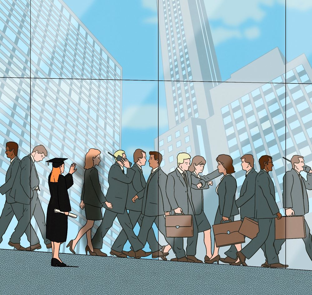 A graduate touches a glass building with office workers and high rise building in it