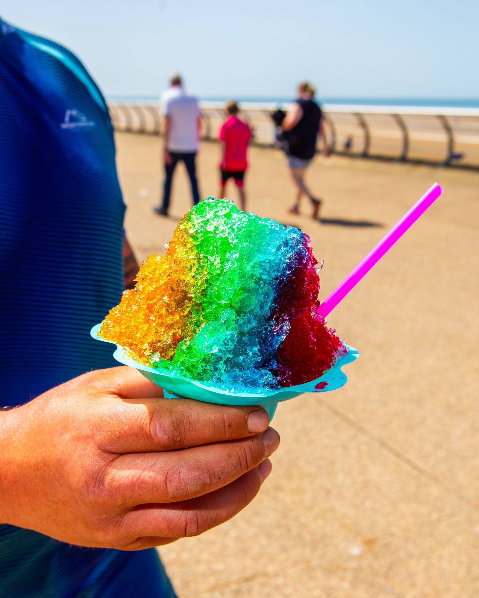 A person holding a multicolored snow cone.