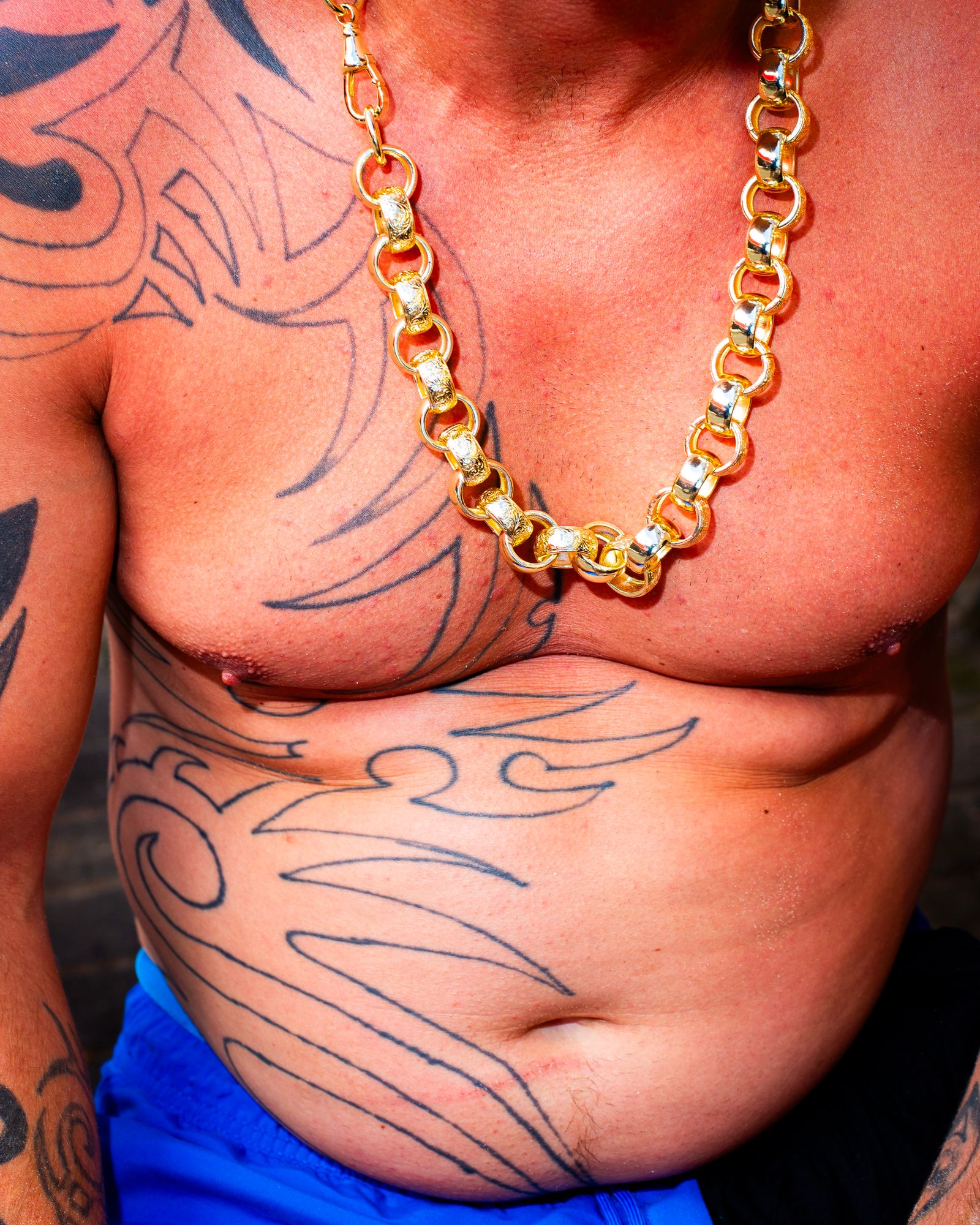 A shirtless man with a gold necklace.