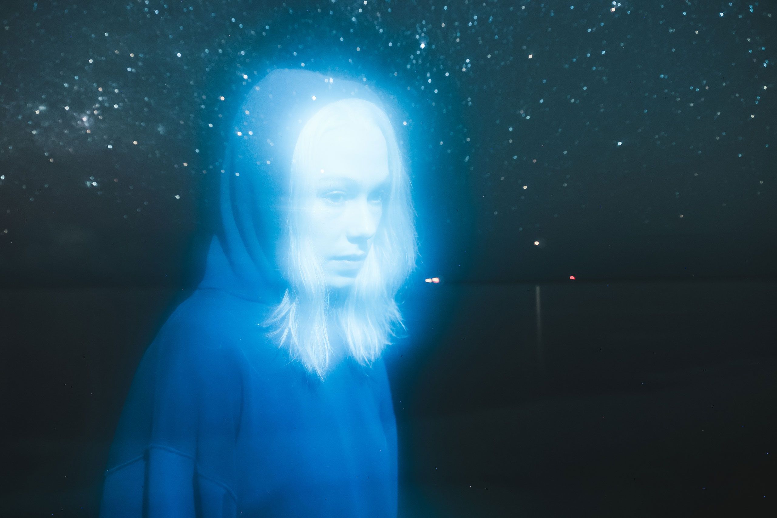 Phoebe Bridgers in hoodie in blue night landscape